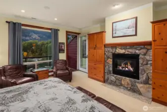2nd Ensuite bedroom with cozy fireplace, built-in cabinetry, and private deck access, capturing beautiful river and mountain views.