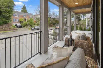 Covered front porch offers a welcoming perch above the street, with space to sit back, unwind, and enjoy the neighborhood setting.