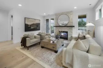 This angle captures the warmth of the great room, where soft natural light, layered design, and a central fireplace create an inviting everyday retreat.