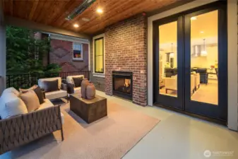 Covered outdoor living extends the main level with a fireplace, rich wood ceiling, and a private setting ideal for relaxed evenings or easy entertaining.