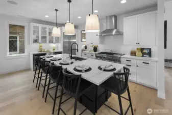 The kitchen pairs crisp cabinetry, professional-grade stainless appliances, and a large island with seating, delivering style and function at the heart of the home.