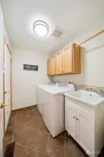 The dedicated laundry space includes cabinetry storage, a hanging rack, and utility sink.