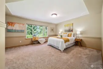 The dreamy primary bedroom boasts a stunning coffered ceiling and expansive windows offering picturesque views of the beautiful backyard.