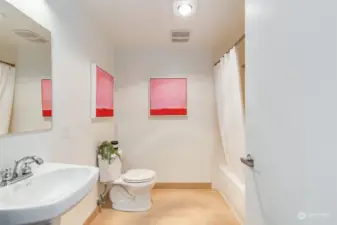 Modern full bath with ceramic tile floors and  full size washer/dryer.