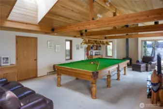 Snooker table (larger than pool table) room with door to wood storage for the wood stove. Slider to deck just out of sight to right of brown chair.  Pocket doors can separate this room from Great Room.
