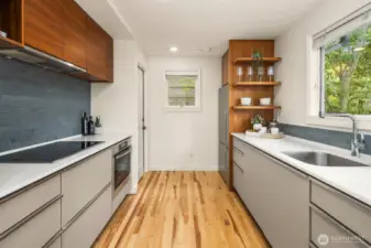 Kitchen with sleek cabinets, open shelving + picture view windows.