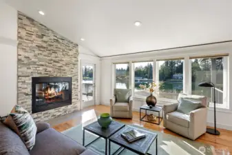 Sun soaked Great Room with hardwood floors and gas fireplace with stone surround