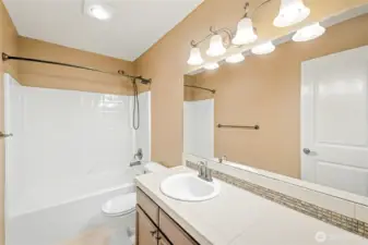 Upstairs full sized guest bathroom with ample storage and counter space.