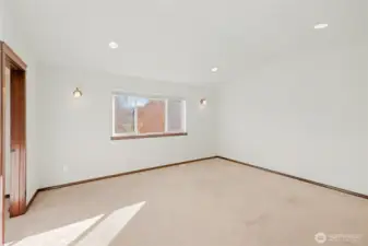 The spacious primary bedroom offers plenty of room to relax, with vaulted ceilings, recessed lighting and large window that floods the space with natural light.