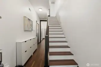 Bright entry foyer featuring hardwood flooring and a clean-lined staircase to the main living level.