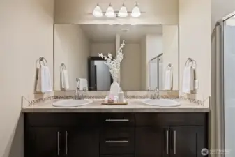 Dual-sink vanity in primary bathroom with granite counters and ample storage.