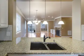 Detailed description of the image: This photo captures the expansive openness of the home, showcasing a welcoming perspective from the kitchen. The shot provides a clear view that extends seamlessly from the kitchen into both the dining and living room areas, highlighting the interconnectedness and flow of the interior spaces.