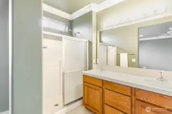 Primary bath with extended shower, double sinks, and private toilet area.