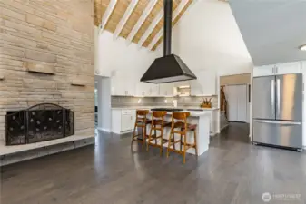 The floor-to-ceiling fireplace and professional-grade kitchen create a breathtaking central hub for the home