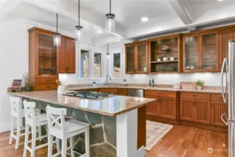 The kitchen boasts slab granite countertops and handsome cabinetry with a nice blend of open shelving and glass doors for display