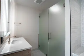 Twin bathroom sinks in the en suite primary bathroom with halo-illuminated mirrors and separate toilet area with privacy glass doors.