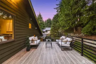 Expansive deck overlooking a private, tree-lined backyard with mature landscaping and patio—perfect for relaxing, entertaining, or gardening.
