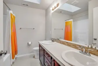 Well-dressed full main bath has a double sink vanity and skylight serving upper-level bedrooms.