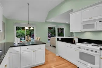 Light, bright kitchen with paneled white cabinets, shiny-brass hardware. Grocery pantry with paneled Quaker door, coated ventilated wire shelving. Oak-hardwood floor in kitchen extends into the breakfast area. Maytag® bottom freezer refrigerator. Upgraded countertops with full bullnose finished edges. GE® range-oven with GE® Spacemaker XL microwave oven above. Kenmore® dishwasher. Undermounted stainless-steel double sinks with In-Sink-Erator® food waste disposal, brushed-nickel faucet, big window for natural light. Vaulted ceiling with recessed lighting. Breakfast area with upgraded breakfast countertop with full bullnose finished edge. Oak-hardwood floor. Alabaster-style chandelier. Sliding glass door with two-inch blinds, and screen door that opens to large aggregate patio and bordered by pavers. Very private, fully fenced Arboretum-style backyard, with wonderful water feature.