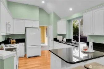 Light, bright kitchen with paneled white cabinets, shiny-brass hardware. Grocery pantry with paneled Quaker door, coated ventilated wire shelving. Oak-hardwood floor in kitchen extends into the breakfast area. Maytag® bottom freezer refrigerator. Upgraded countertops with full bullnose finished edges. GE® range-oven with GE® Spacemaker XL microwave oven above. Kenmore® dishwasher. Undermounted stainless-steel double sinks with In-Sink-Erator® food waste disposal, brushed-nickel faucet, big window for natural light. Vaulted ceiling with recessed lighting.