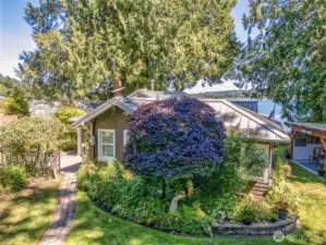 Lush mature landscaping surrounds the property with blooming shrubs, vibrant perennials, and towering trees creating a sense of privacy and timeless beauty.