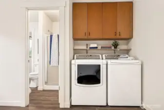The primary 3/4 bath has two doors. One to the primary bedroom and one to this utility room for easy bathroom access when coming in from out of doors.  The included washer and dryer enjoy great ovehead storage too!