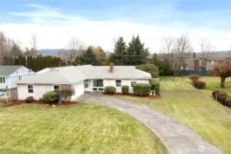 Elevated view of front yard, home and extra parking to the right of the driveway. Large rhododendron behind home on the right side