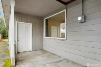 2nd Patio area with door from shop on the left and large window from family room on the right. Concrete walkway to back yard on the far left & it continues the other direction to the front yard too