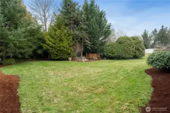 Large back yard at end of concrete walkway along west side of home.