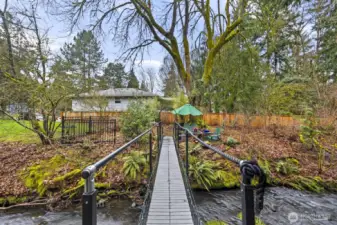 The babbling creek, gorgeous greenery, & dappled shade from towering trees create an outdoor space unlike any other. Yes, this is your walking bridge over to the other part of the backyard!