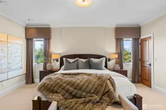 A serene sanctuary for rest and relaxation. This primary suite features soaring ceilings and natural light from tall windows flanking the bed, paired with it's own en-suite bathroom.