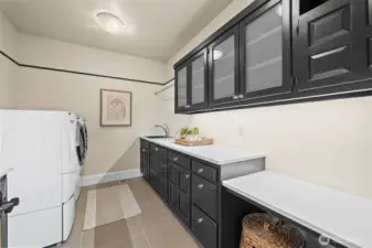 Utility meets high-end aesthetics. Striking black cabinetry with elegant fogged-glass inserts elevates the laundry room into a sophisticated workspace that mirrors the home’s overall modern design.