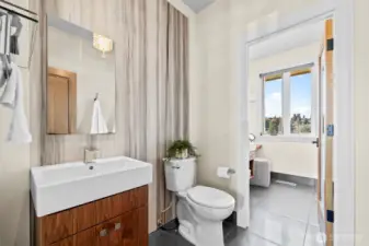 This shared suite echoes the primary en-suite’s grandeur, utilizing a dramatic marble slab to bring texture and light-reflecting elegance to the vanity area.