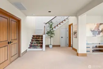A masterful use of color and texture. The custom-designed red carpeting on the staircase serves as a bold sculptural element, creating a sophisticated focal point that leads you into the expansive lower-level retreat.