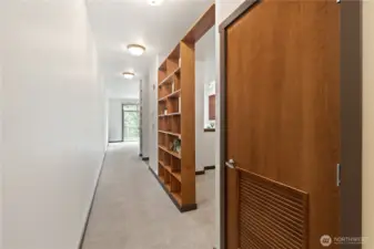 Hallway. On right are laundry/utility closet, bedroom area and kitchen entry, flowing to living area