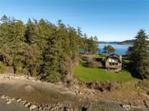 Waterfront home with private beach and tidelands. Beach at low tide in the foreground, Swifts Bay behind house