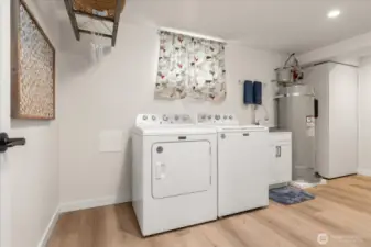 A laundry room with pizzazz, offering plenty of space for a freezer or second brand new washer and dryer, built in ironing board and built in collapsible folding table