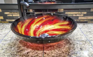 Fancy designer sink in Primary bathroom with granite countertops and mosaic backsplash.