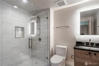 The second bedroom includes its own en suite bathroom with oversized shower and halo mirror vanity.