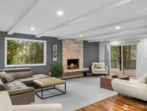 This expansive open-concept living room defines luxury with the ceiling and designer exposed beams creating an inviting atmosphere. The sliding doors offer a seamless indoor-outdoor flow to your private oversized deck overlooking Carkeek Park.