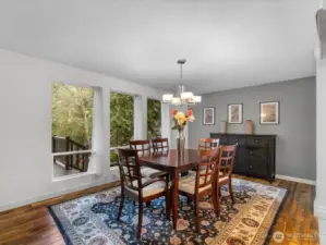 The dining area is bathed in abundant natural light, framed by expansive windows that create an airy, inviting ambiance. Sunlight pours in to highlight the space’s openness and understated elegance.