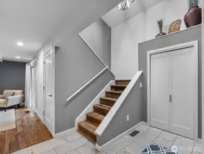 A gracious, light-filled foyer sets a serene and welcoming tone, featuring soaring ceilings with skylights that bathe the space in natural light and a convenient coat closet just off the entry. Rich reclaimed hardwood floors paired with elegant porcelain tile and travertine inlays create a warm, timeless first impression.