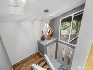 Experience the ultimate in modern sophistication with this sun-drenched, two-story foyer featuring a designer geometric pendant; notice the skylights flooding the foyer with natural light, creating a bright, airy atmosphere that instantly elevates the home's entrance.