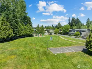 Large grassy field with playground and basketball court