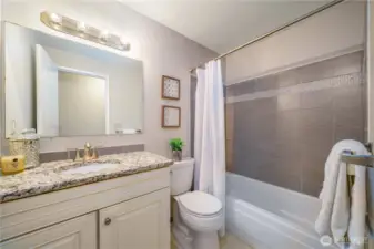 Across the hall, the full guest bath also includes granite counters and updated finishes.
