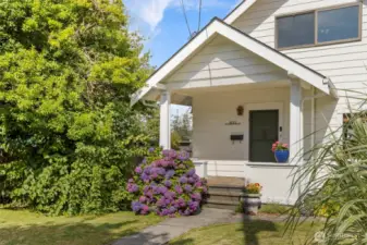 Covered front porch surrounded by mature landscaping
