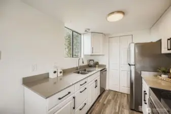 Beautifully updated kitchen featuring newer cabinets, sleek quartz countertops, an under-mounted sink, brand new appliances, and a spacious pantry for added storage.