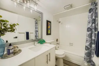 Beautifully updated bathroom featuring modern finishes, quartz surfaces, and a large soaking tub with shower combo for ultimate relaxation