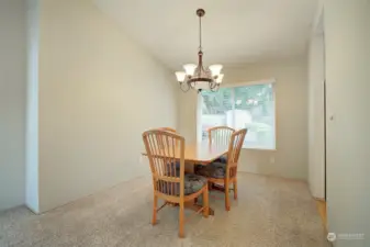 The dining room is adjacent to the living room, featuring vaulted ceilings, and a view of the backyard landscape.