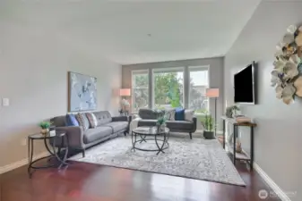 Hardwood flooring, spacious open living room, large light-filled window, and picture perfect yard.